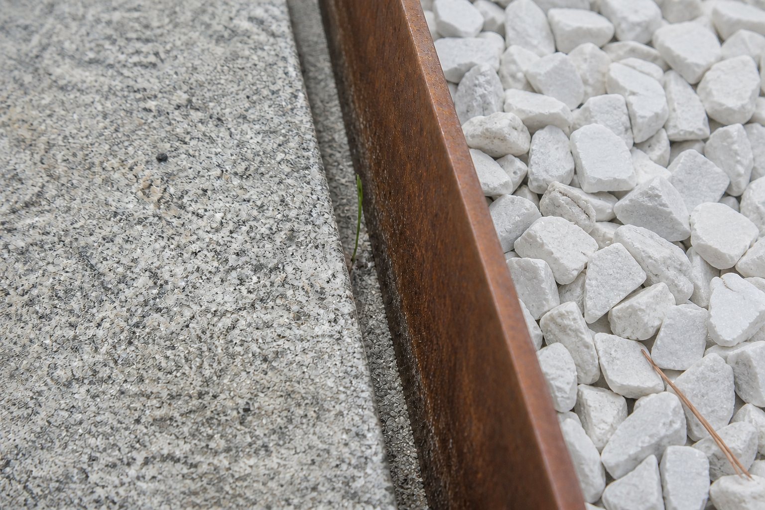 Korteno plieno juosta tarp betono dangos ir balto skaldos lauko
